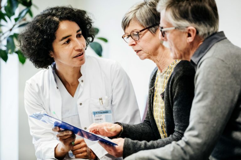 A clinical doctor giving some test results to a couple of elderly patients in hospital.