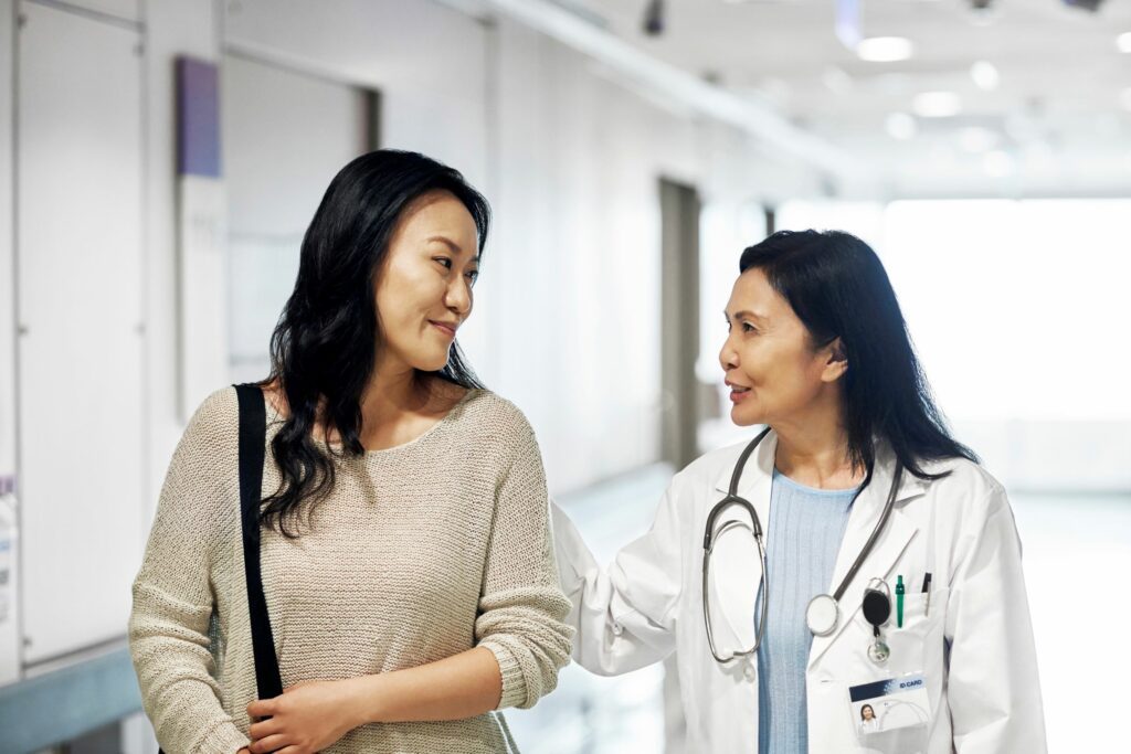 A woman speaking to a female doctor while walking down a hall.