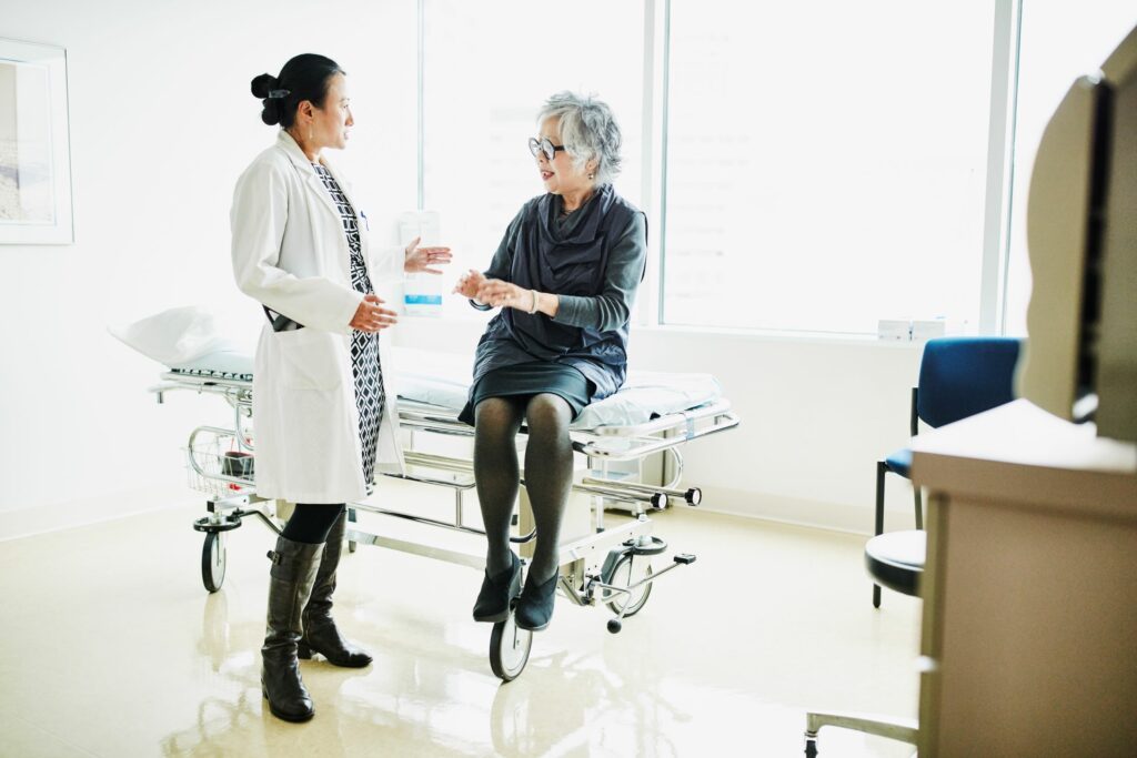 Older woman sitting on a gurney speaking to a doctor.