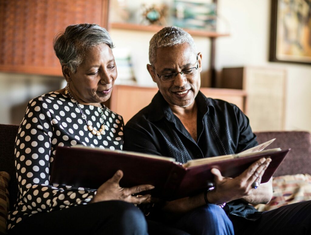 Older man and woman looking at a photo album on a couch.