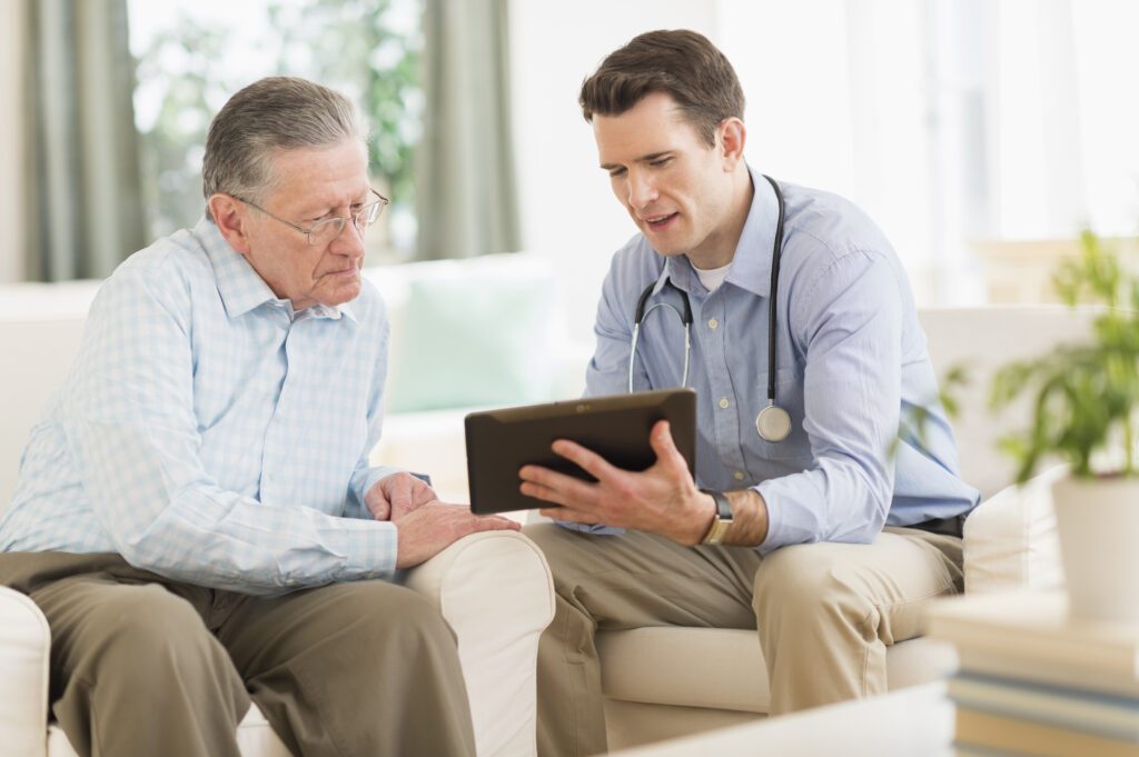 Caucasian doctor and patient using digital tablet at home
