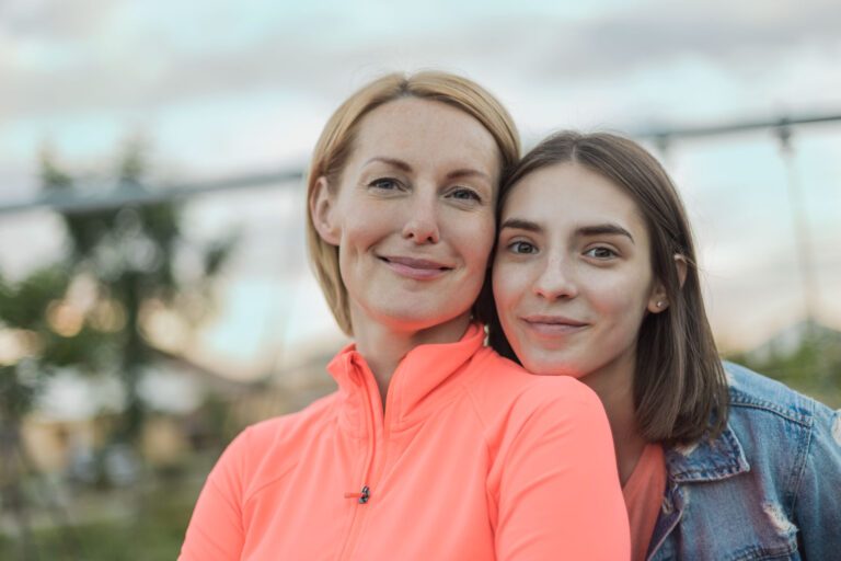Portrait of smiling mother and daughter against sky at park