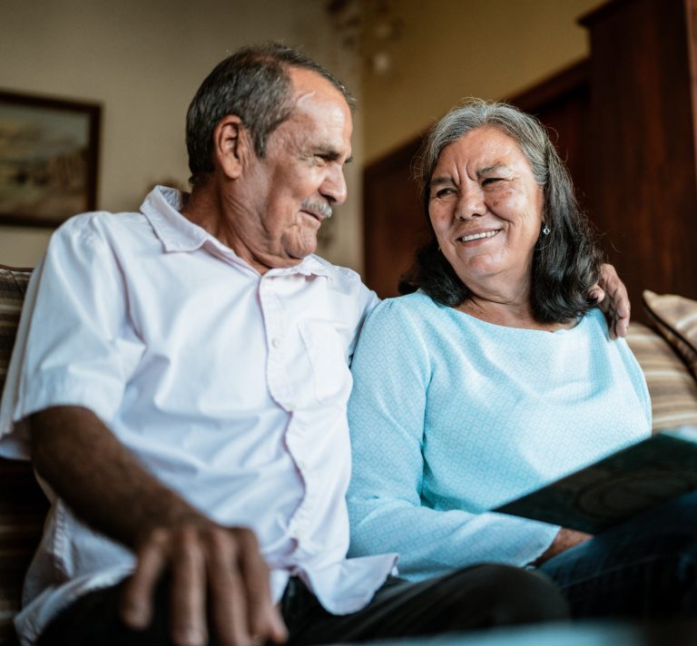 Senior couple looking a photo album sitting on sofa in the living room